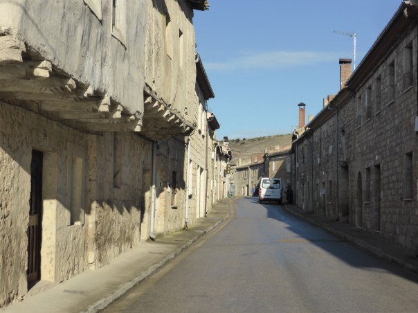 View of the main (and only ) street as we left   Hornillios. Loook at the old floor joists extending out to hold the next floor - hundreds of yeas old. the white truck:  kind of neat: thats the bread truck. There is no bakery in town so the bread man drives every block,sounding his horn and all those who want fresh bread can come out to buy it. And then visit with their neighbours!